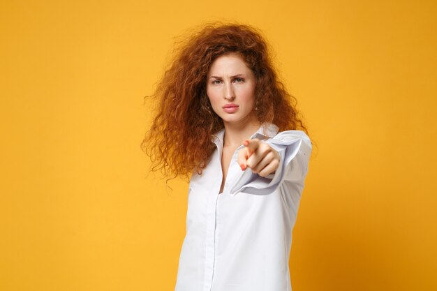 Ontevreden jonge roodharige vrouw meisje in casual wit overhemd poseren geïsoleerd op geel oranje muur