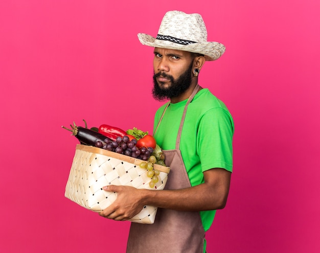 Ontevreden jonge tuinman Afro-Amerikaanse man met tuinhoed met groentemand