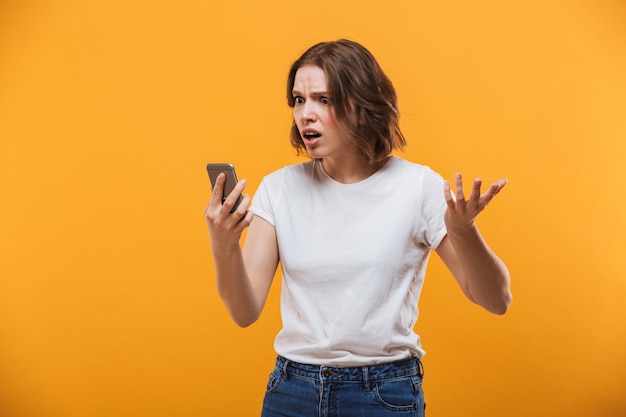 Ontevreden jonge vrouw die mobiele telefoon met behulp van