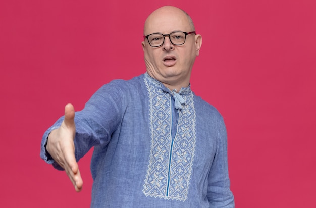 Ontevreden volwassen man in blauw shirt met een bril die zijn hand uitsteekt