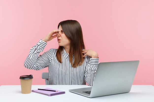 Ontevreden vrouw werknemer adem inhouden knijpen haar neus met vingers verward met walgelijke geur wil niet ademen werken in vuile kantoor Indoor studio shot geïsoleerd op roze achtergrond