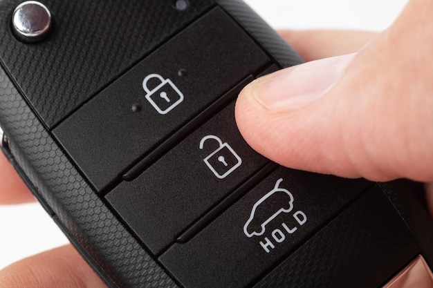 Foto ontgrendelen van een auto met knop op de sleutelhanger man's hand houdt autosleutel op witte achtergrond close-up
