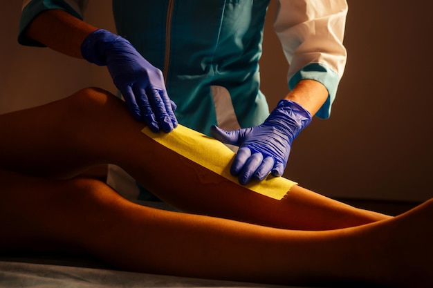 Ontharing spa procedure. Vrouwenhaar verwijderen waxing shugaing en wax strips. Epileercliënt en schoonheidsspecialiste professionele suikerspin voet in de spa salon