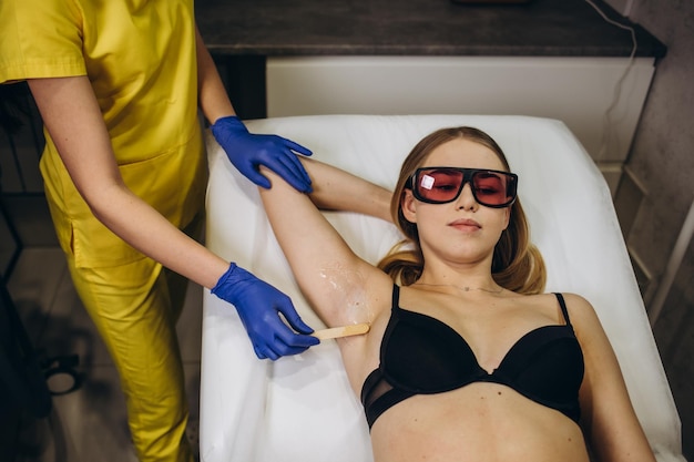Ontharingsgel aanbrengen onder de armen Vrouw tijdens een laserepilatiesessie met een moderne laser in een schoonheidsstudio