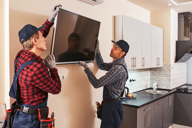 Foto ontmanteling van elektronische apparatuur twee technici verwijderen plasma in keuken