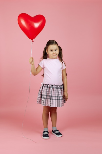 ontmoedigd meisje in een roze jurk met een rode hartvormige ballon