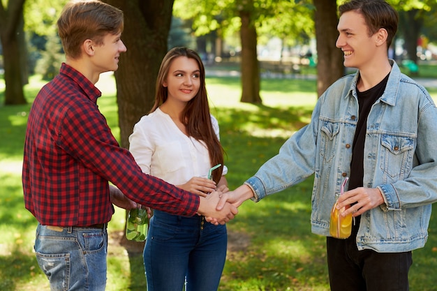 ontmoeting met vriend. vrolijke jonge mensen die er gelukkig uitzien terwijl ze handen schudden