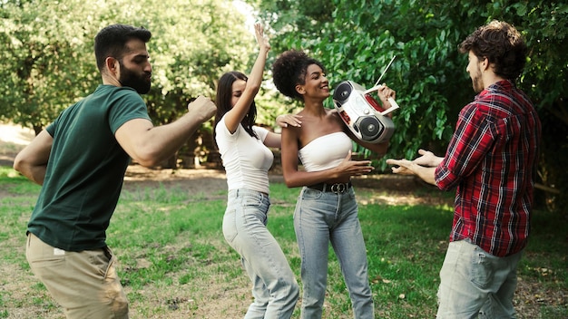 Ontmoeting van jonge mensen die samen plezier hebben, dansen in het park en luisteren naar muziek met een boombox. Vrienden die het concept van gezonde buitenspeelactiviteiten doen.