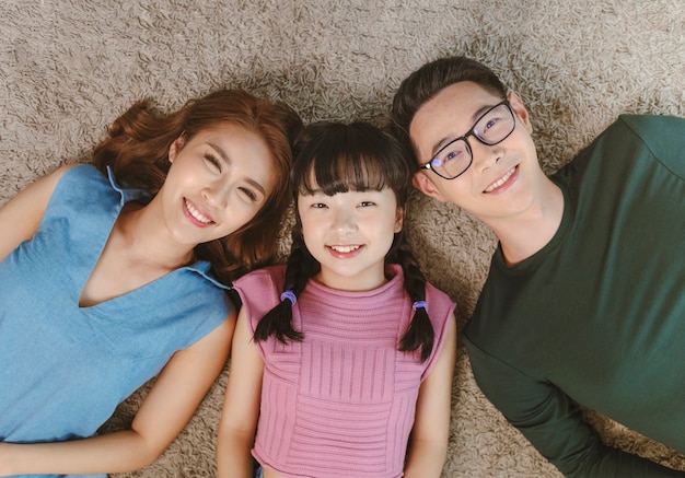 Ontspan aziatische familie tot met gelukkig en glimlach op tapijt in de huiskamer. bovenaanzicht