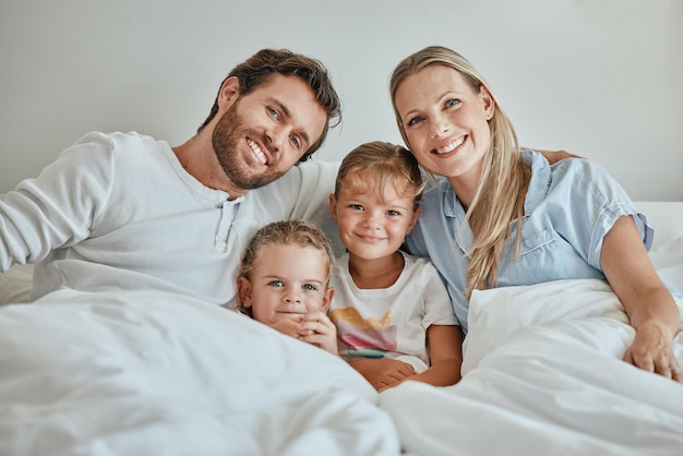 Ontspan gelukkig en portret van familie in bed in de ochtend voor ondersteuning bij het wakker worden en quality time samen Glimlach vrede en weekend met ouders en kinderen thuis voor hechting, verbinding en zorg