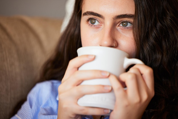 Ontspan kalm en vrouw die koffie drinkt in de woonkamer op een bank in haar moderne huis in Australië Weekenddenken en dame die geniet van een kopje warme cafeïne of theedrank in haar lounge