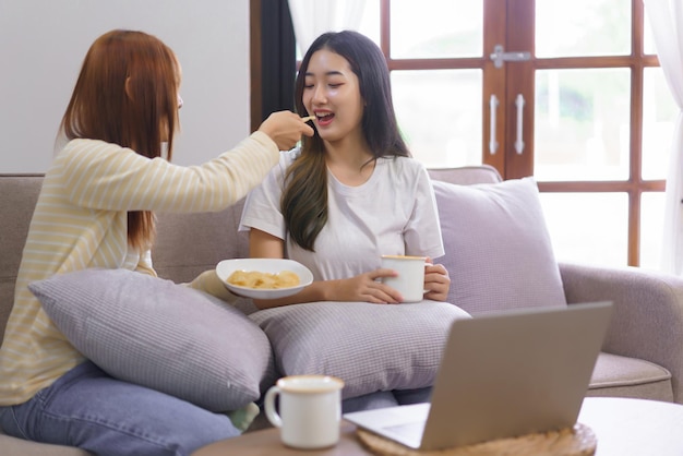 Ontspan thuis concept Lesbisch stel drinkt koffie en geeft snack aan vriendin in woonkamer
