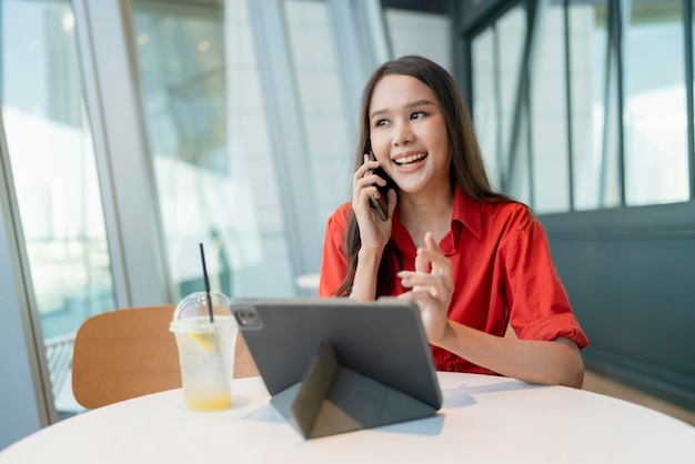 Ontspan vrije tijd aantrekkelijke slimme aziatische vrouwelijke freelance ondernemer glimlach en geniet van het werken met smartphone en laptop in café met vervagen stad zakelijke digitale nomade casual ideeën concept