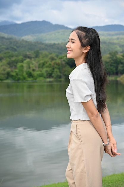 Ontspannen Aziatische vrouw kijkt naar het prachtige uitzicht op de verbazingwekkende groene berg en het meer