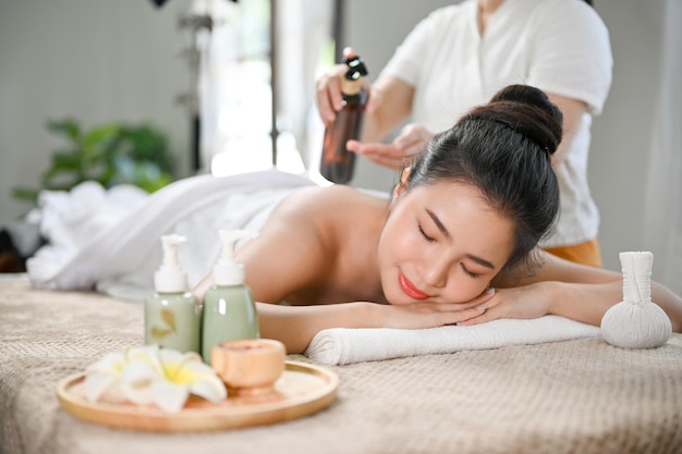 Ontspannen Aziatische vrouw liggend op een massagetafel die lichaamsmassage ontvangt en geniet van de Thaise spa in de salon