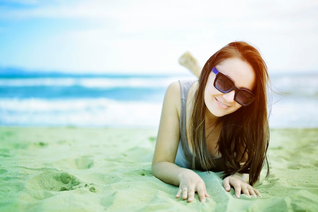 ontspannen en positieve vrouw liggend op de zandkleurige foto