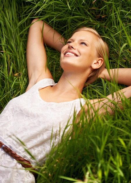 Ontspannen in de rustige omhelzing van de natuur Een aantrekkelijke jonge vrouw liggend in een open groen veld