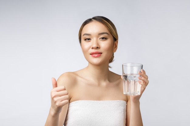 Ontspannen jonge glimlachende vrouw die schoon water drinkt.