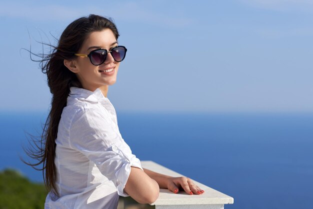 ontspannen jonge mooie vrouw voor luxe moderne huisvilla op balkon op zonnige dag