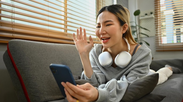 Ontspannen jonge vrouw die met de hand zwaait en videobellen op smartphone Mensen technologie en communicatie