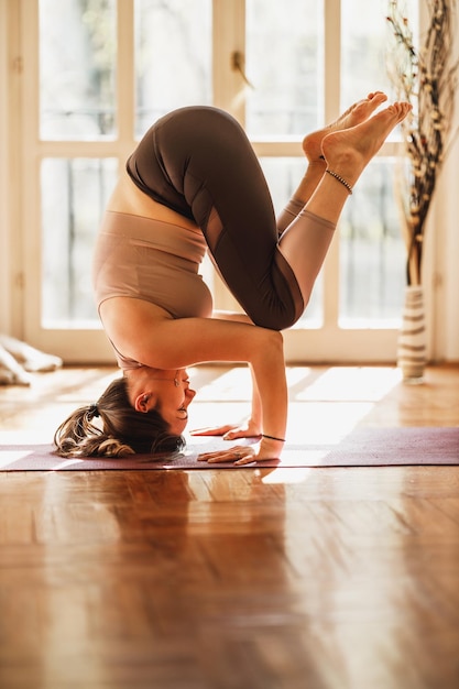 Foto ontspannen jonge vrouw die thuis yoga beoefent.