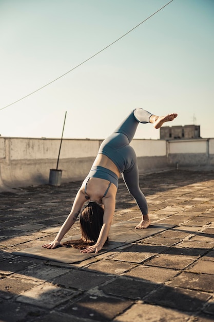 Ontspannen jonge vrouw die yoga beoefent op een dakterras.