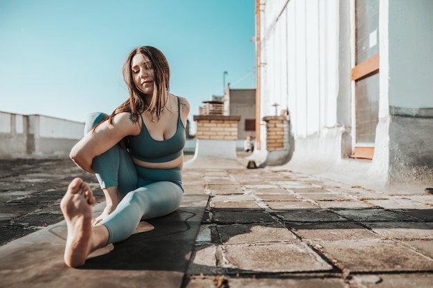 Ontspannen jonge vrouw die yoga rekoefeningen beoefent op een dakterras.