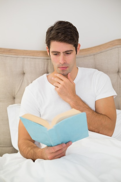 Ontspannen jongeman leesboek in bed