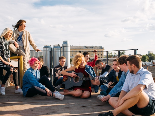 Ontspannen lachende jongeren reizen door Europa. Zittend op een dak zingend en genietend van hun reis. Jeugd levensstijl
