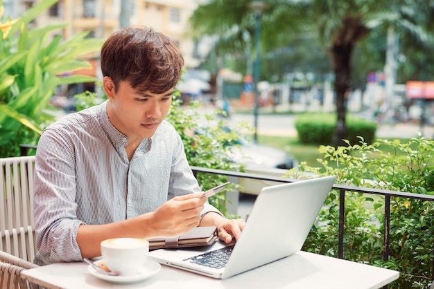 Ontspannen man schrijven in een laptop in een coffeeshop