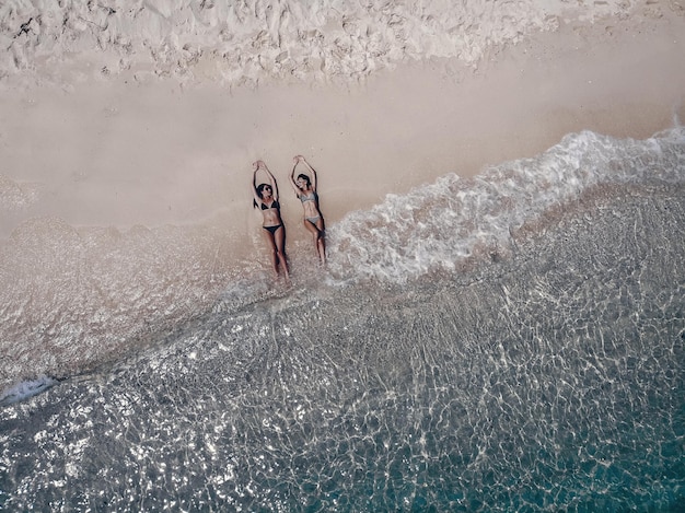 Ontspannen meisje genieten van tropisch strand in de buurt van droge oude boom. Mooie brunette meisje in een zwarte mode zwembroek zonnebaden op een strand. Phuket. Thailand.