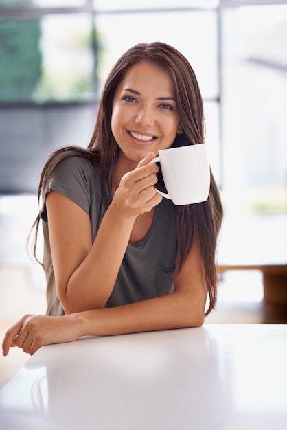 Ontspannen met een kopje Java Shot van een aantrekkelijke jonge vrouw die thuis een kopje koffie drinkt