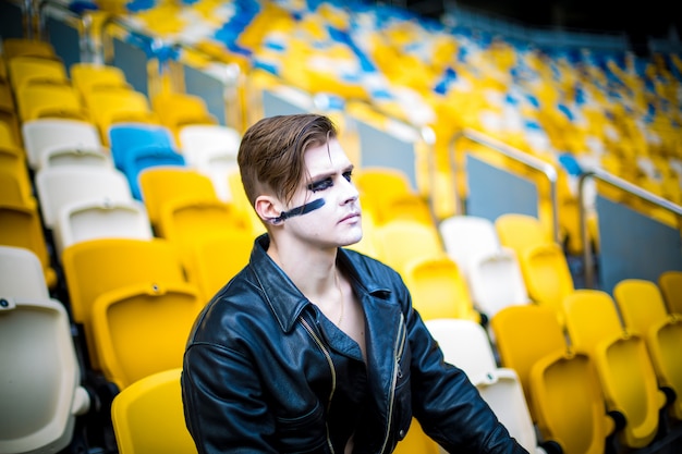 Ontspannen mode voor mannen in leren jas poseren zittend in het stadion