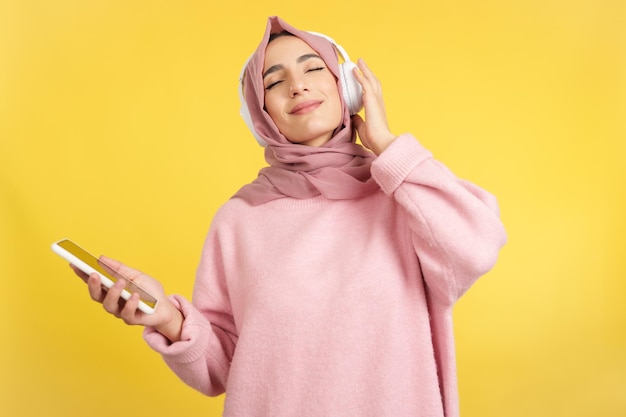 Ontspannen moslimvrouw luisteren naar muziek met mobiel