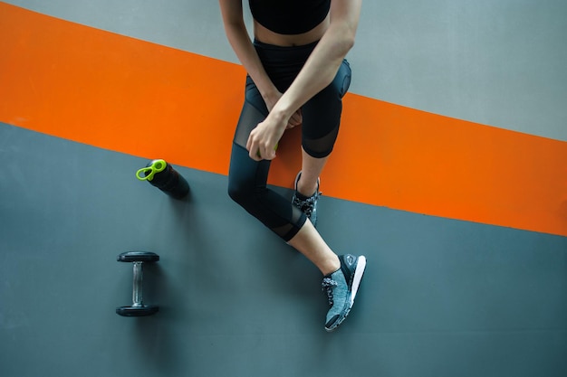 Ontspannen na training.young vrouw zitten met halter en eiwit shake fles op gym.young vrouw op sportschool een pauze nemen van workout.top uitzicht.