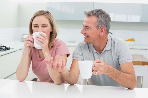 Ontspannen paar met koffiekoppen in keuken