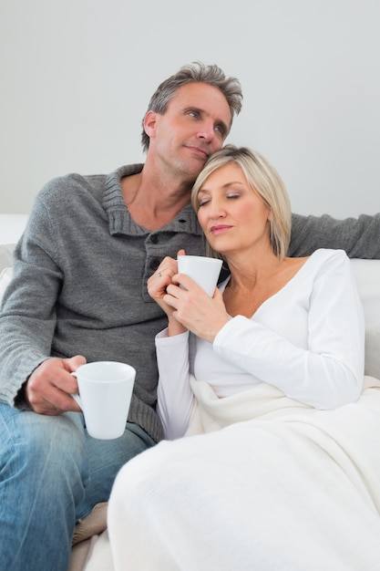 Ontspannen paar met koffiekoppen in woonkamer