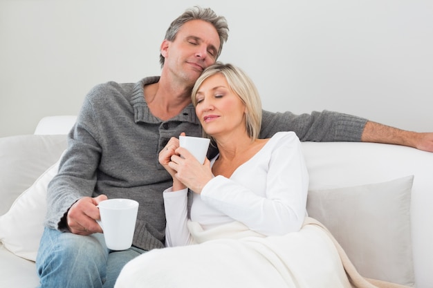 Ontspannen paar met koffiekoppen in woonkamer