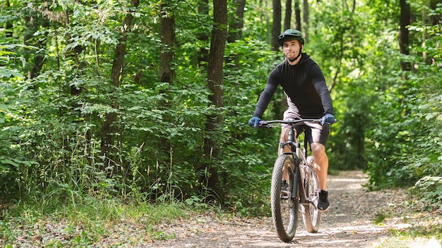 Ontspannen sportman die graag over het bospad fietst