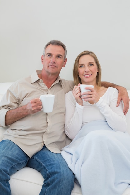 Ontspannen verliefde paar met koffie kopjes in de woonkamer