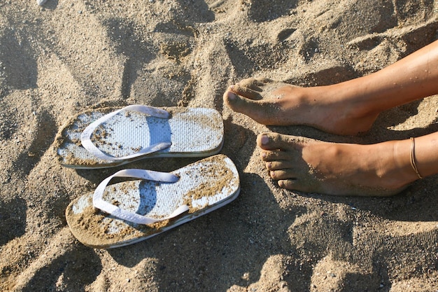 Foto ontspannen voeten op het zand met slippers