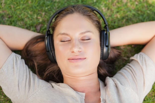 Foto ontspannen vrouw die op het gazon ligt terwijl het luisteren aan muziek