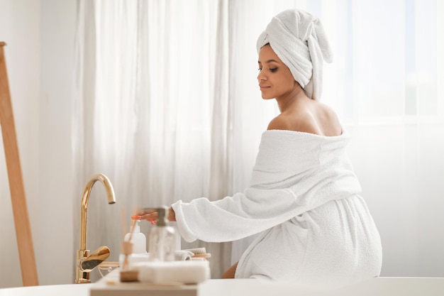 Ontspannen vrouw genieten van lichaamsverzorging rituelen met behulp van cosmetica zittend in de badkamer