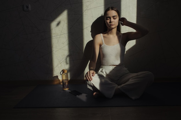 ontspannen vrouw mediteert met gesloten ogen in Lotus pose terwijl ze yoga beoefent op mat