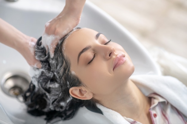 Ontspannen. vrouw op zoek ontspannen terwijl haarstylist haar haren wast