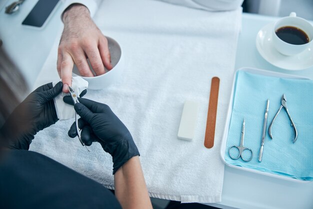 Ontspannen zakenman die schoonheidssalon bezoekt terwijl hij zijn hand in het water houdt en manicure doet