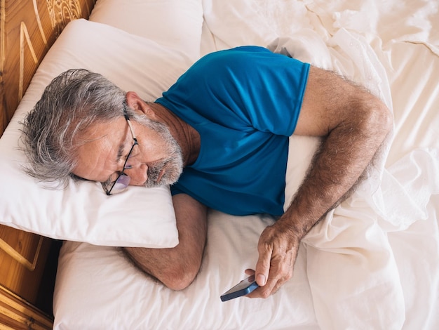 Ontspannen zieke man met baard liggend bellende telefoon in bed