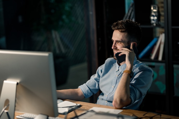 Ontspannende mens die op telefoon in bureau spreekt