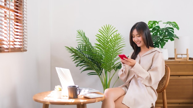 Ontspanning lifestyle concept Jonge Aziatische vrouw gebruikt smartphone om te chatten na thuis werken