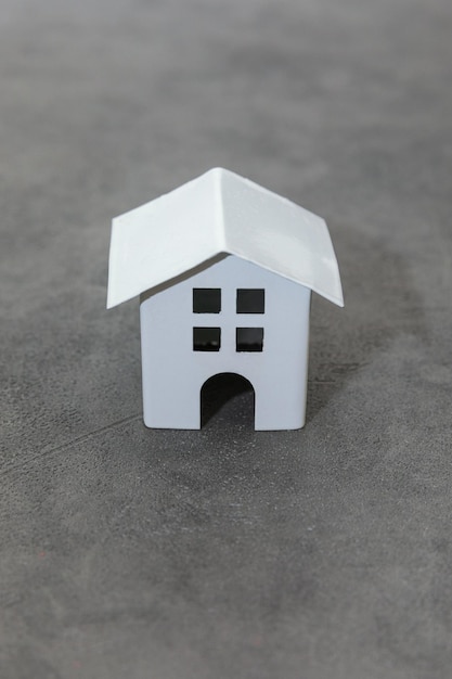 Ontwerp eenvoudig met miniatuur wit speelgoedmodelhuis op betonnen steengrijze achtergrond hypotheekeigenschap